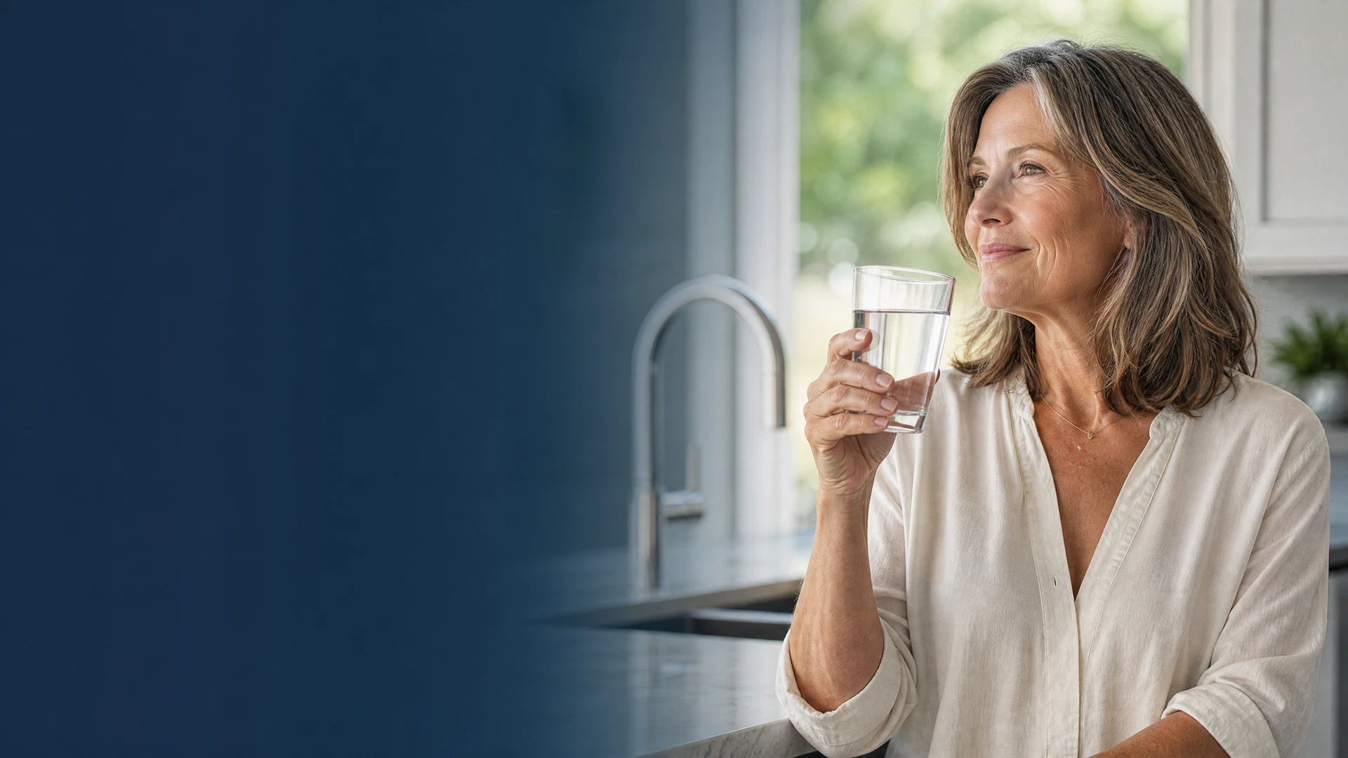 Homeowner enjoying a glass of clear water in a bright modern kitchen